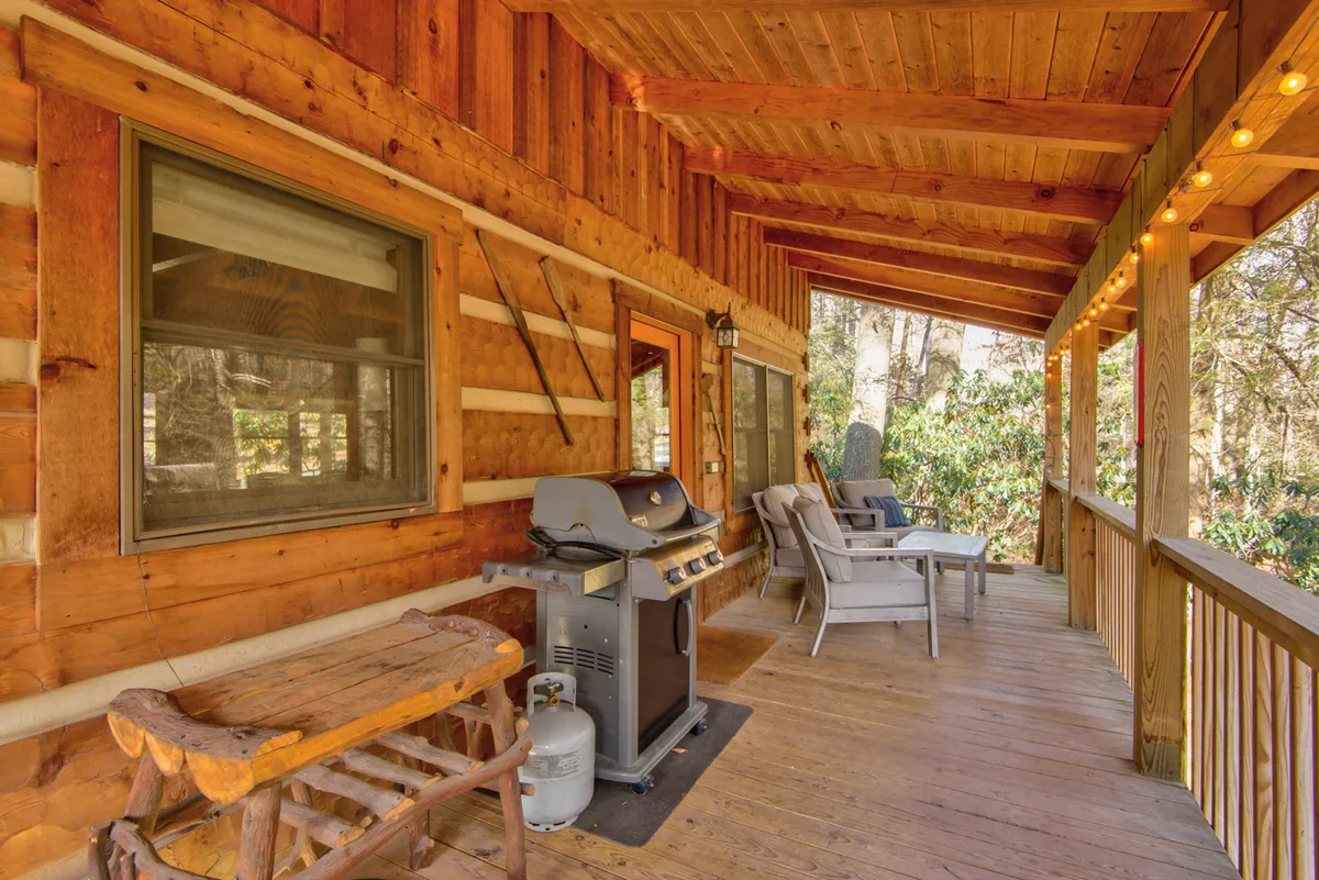The image features a wooden deck with a grill, a table, and a seating area. The setup is perfect for barbecuing, socializing, and enjoying mountain sunsets or starlit evenings outdoors with family or friends.